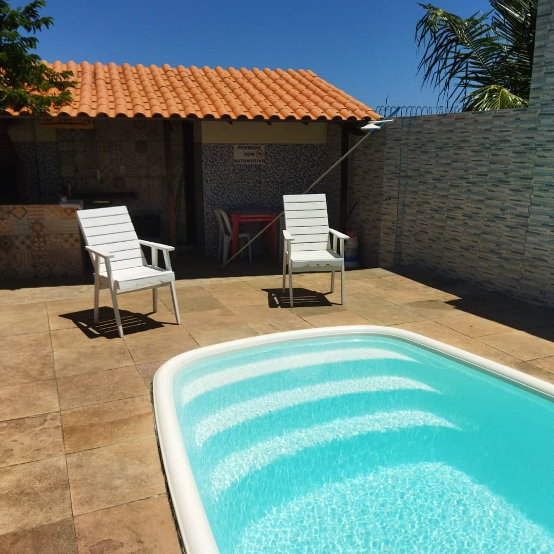 Piscina vista lateral com espreguiçadeiras e área gourmet ao fundo